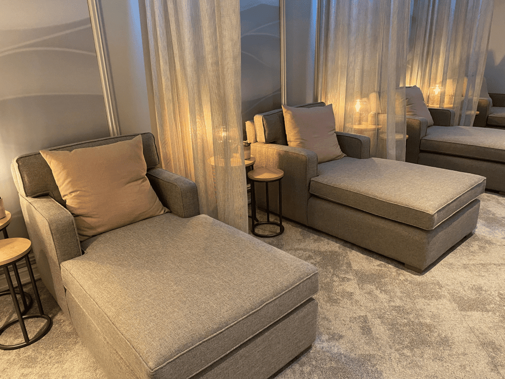 Interior of Aztec Hotel and Spa, a hotel pool and spa area, featuring relaxing and comfortable lounge day beds, lounge chairs, and sofas for a calm and serene atmosphere.